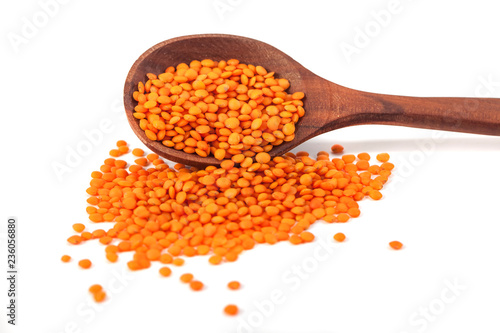 Red lentils in the wooden spoon, isolated on white background