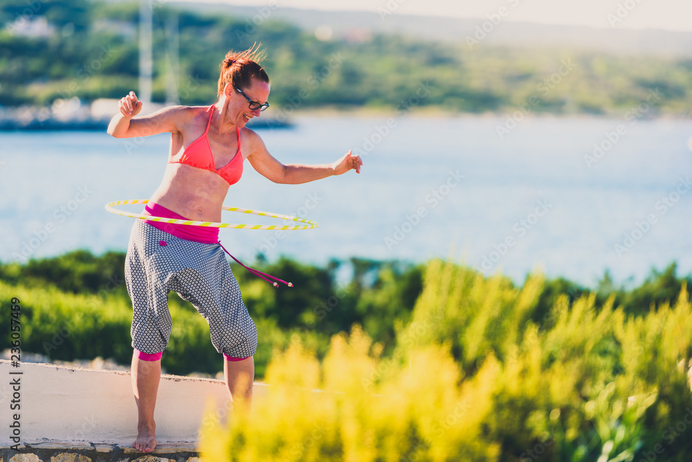 Attractive adult woman is playing with hula hoop in nature. Attractive adult woman is playing with hula hoop in nature.