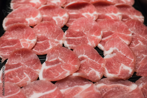 The close up of slide raw pork on a black plate.