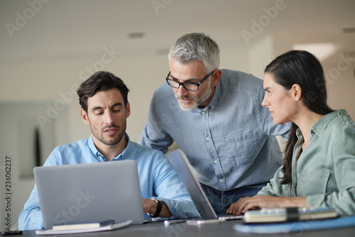  Young colleagues with older boss working with computers