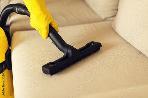 Woman cleaning sofa with yellow vacuum cleaner. Copy space. Clean concept