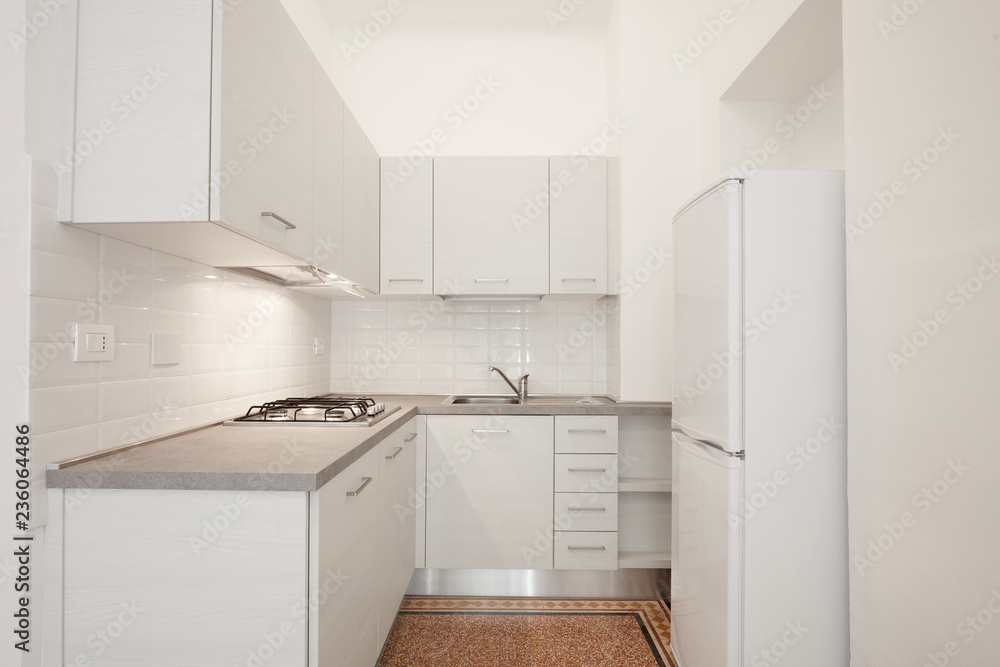 Fototapeta premium White wooden kitchen with gray stone top in renovated apartment interior