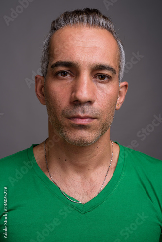 Handsome Persian man with gray hair wearing green t-shirt