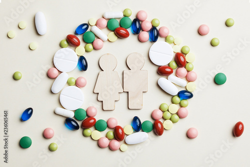 wooden toy man and woman in colorful medicine pills, capsules and tablets circle