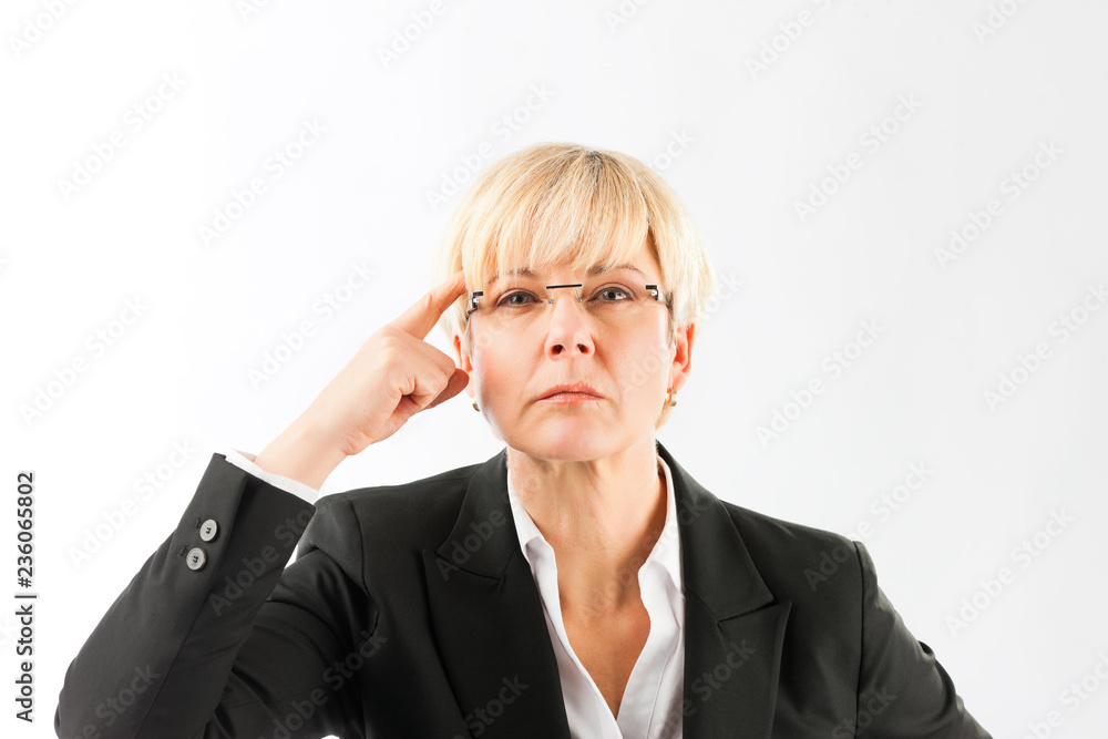 An angry mature businesswoman pointing her finger on forehead over white background An angry mature businesswoman pointing her finger on forehead over white background
