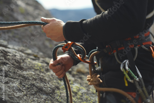 Easy belay-descender device in the hands of a climber closeup. Climbing gear and equipment.