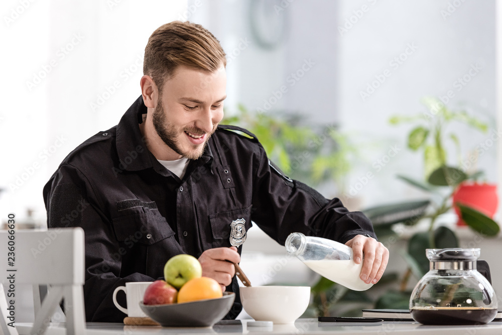 handsome policeman pouring milk into cereal bowl and having breakfast at kitchen handsome policeman pouring milk into cereal bowl and having breakfast at kitchen