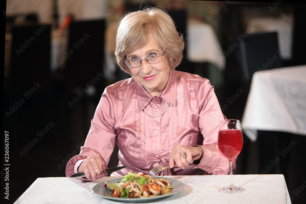 An elderly woman, a beautiful grandmother in a restaurant drinking Morse. Healthy lifestyle. Worthy old age. Beautiful old age and longevity. The concept of longevity and health.