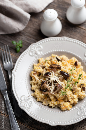 Barley mushroom risotto on plate. Traditional italian cuisine meal  vegetarian risotto with pearl barley and mushrooms on rustic wooden table  top view
