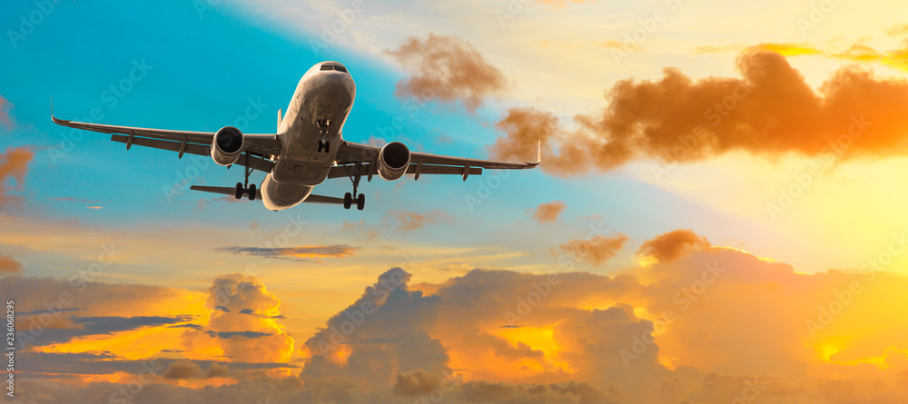 Fototapeta premium Airplane flying above dramatic clouds during sunset