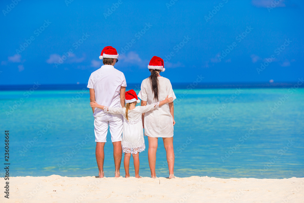 Happy family of three in Santa Hats during tropical vacation