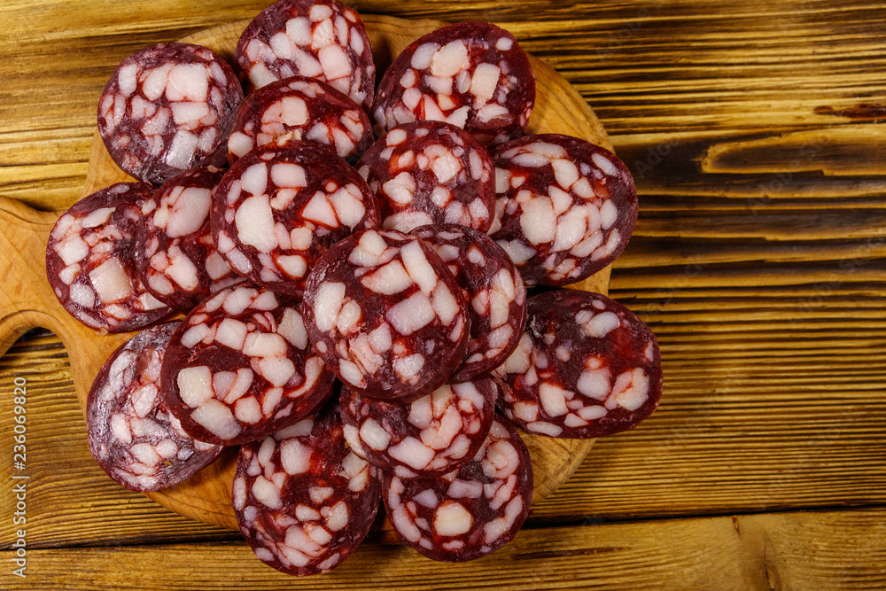 Sliced salami sausage on cutting board on wooden table. Top view Sliced salami sausage on cutting board on wooden table. Top view