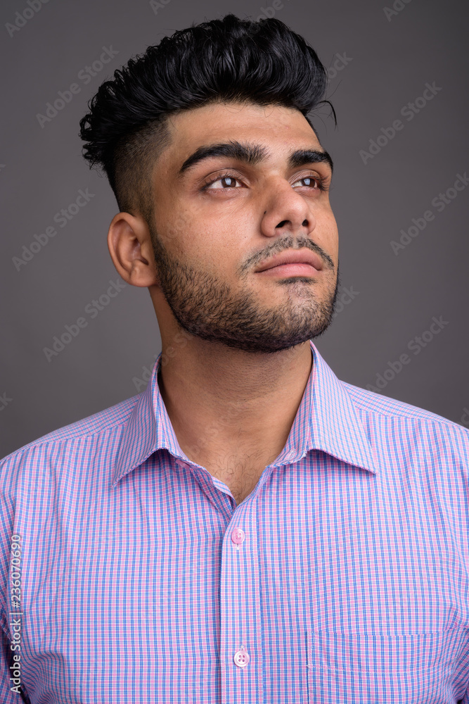 Obraz premium Young handsome Indian businessman against gray background