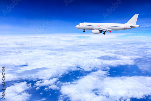 Airplane flying away in to sky high altitude above the white clouds