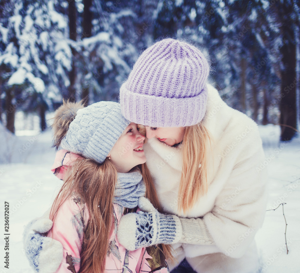 happy mom and little girl hugging in winter forest. New Year