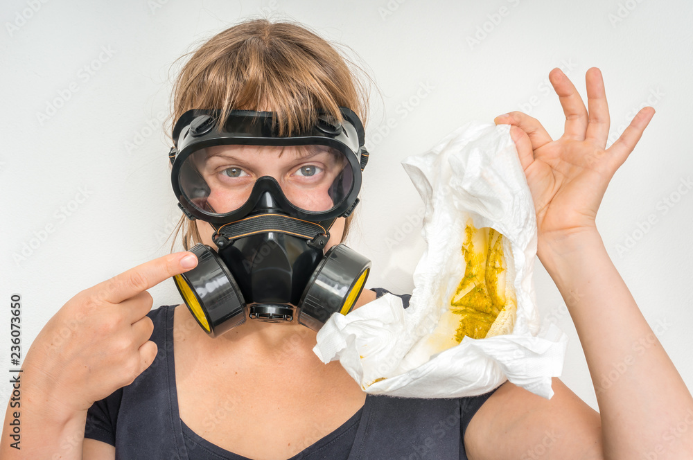 Mother with gas mask changing smelly diaper Mother with gas mask changing smelly diaper