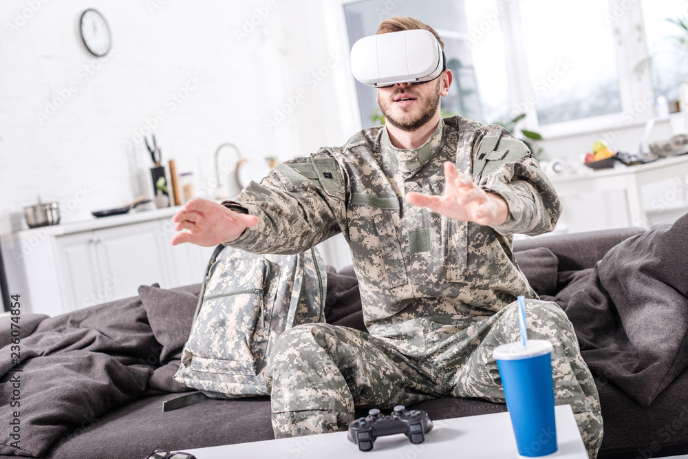 Fototapeta premium army soldier touching air during vr experience on couch