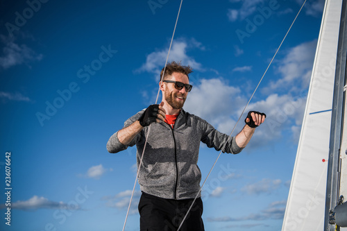 Young man lifting the sail of catamaran during cruising