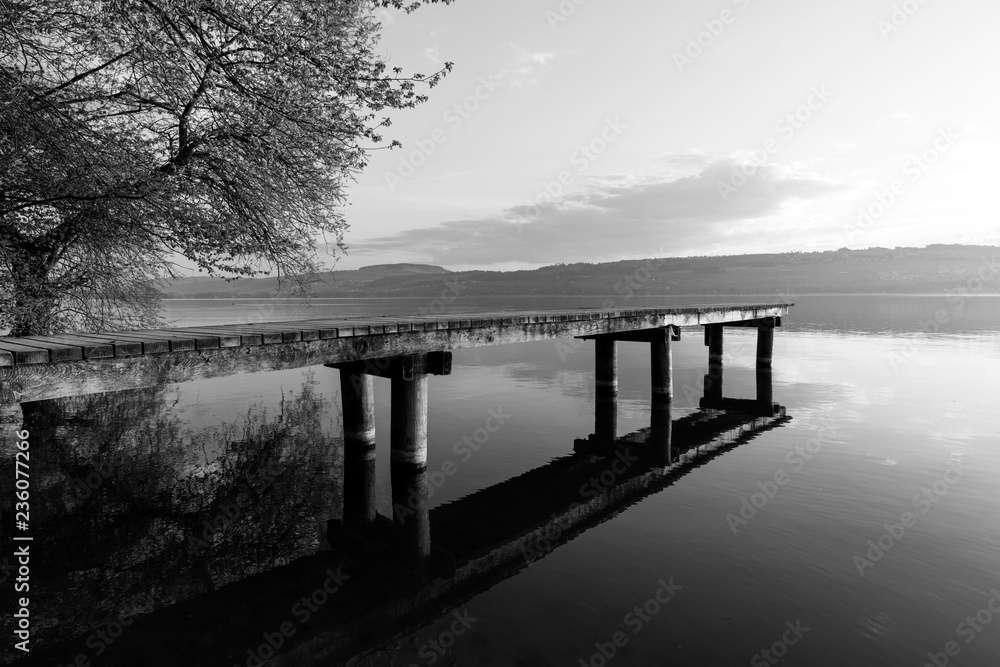 Wonderful morning mood on Lake Sempach in Switzerland. A wooden walkway leads out onto the lake.