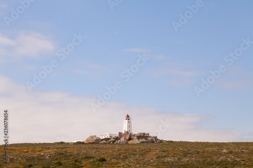 Lighthouse on a rocky hill with big misty sky, copy space