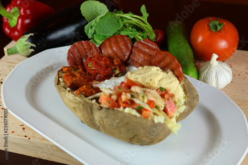 Kumpir - Traditional Turkish meal with baked potato, butter, cheese, bulgur salad, beef sausage and hot spices