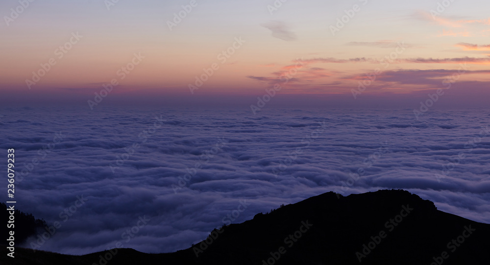 Fototapeta premium Mountain range with visible silhouettes through the morning colorful mist. Abstract background with mountains