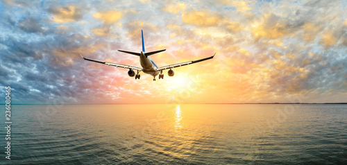 Airplane flying over the sea at sunset © ABCDstock