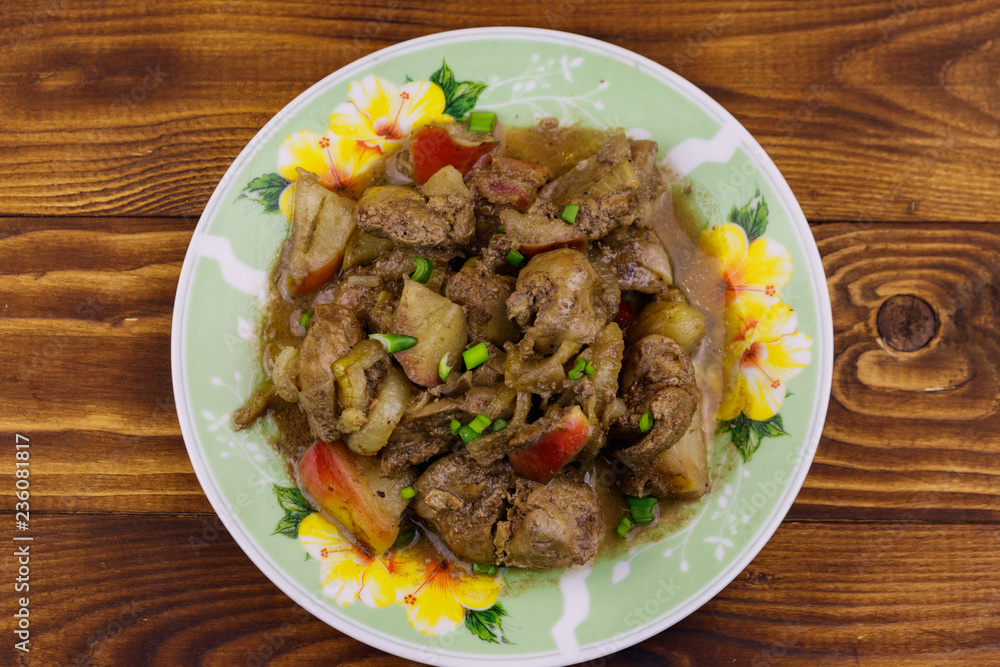 Stewed chicken liver with apple and onion on wooden table Stewed chicken liver with apple and onion on wooden table