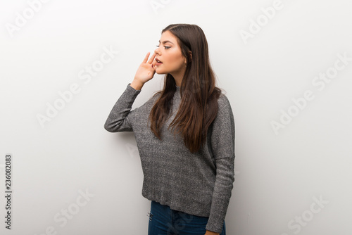 Teenager girl on isolated white backgorund listening to something by putting hand on the ear