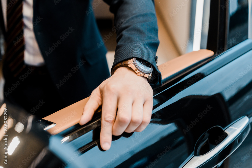 cropped image of businessman with luxury watch holding hand on car door