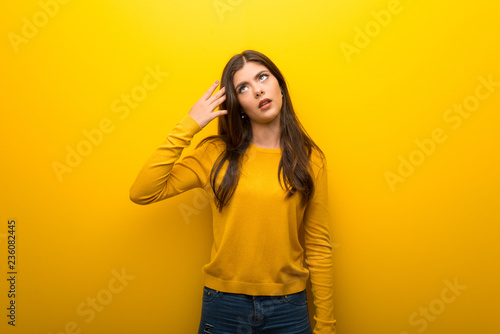 Teenager girl on vibrant yellow background with problems making suicide gesture