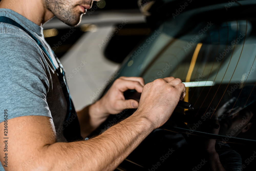 Obraz premium partial view of auto mechanic checking car details at mechanic shop
