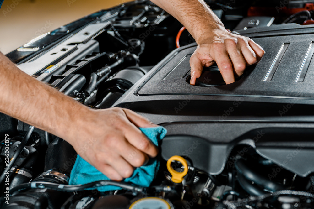 cropped shot of auto mechanic with rag checking automobile