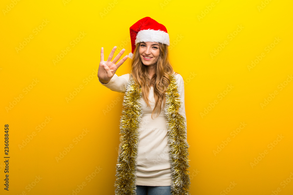 Girl celebrating the christmas holidays on yellow background happy and counting four with fingers Girl celebrating the christmas holidays on yellow background happy and counting four with fingers