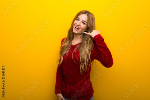 Young girl on vibrant yellow background making phone gesture. Call me back sign