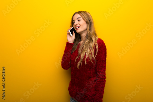 Young girl on vibrant yellow background keeping a conversation with the mobile phone © luismolinero