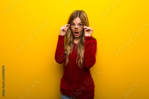 Young girl on vibrant yellow background with glasses and surprised