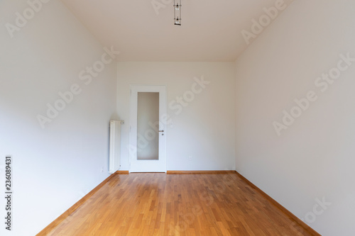 Empty room with white walls  parquet floor and wooden door