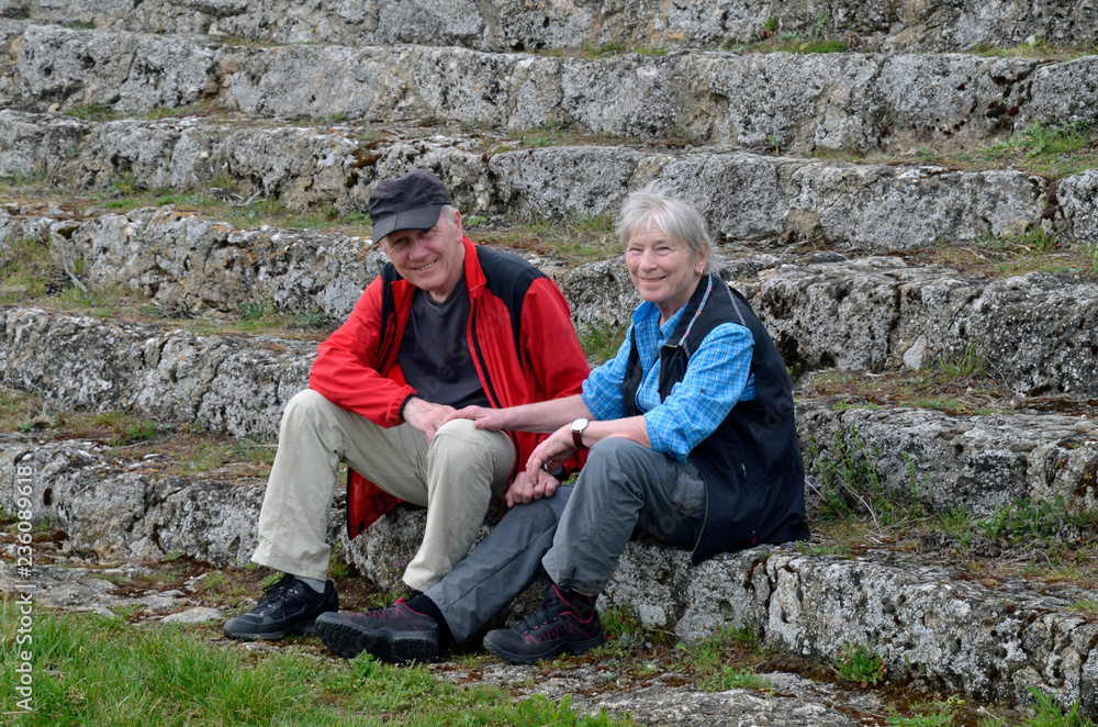 ein älteres paar sitzt auf einer treppe und lächelt in die kamera