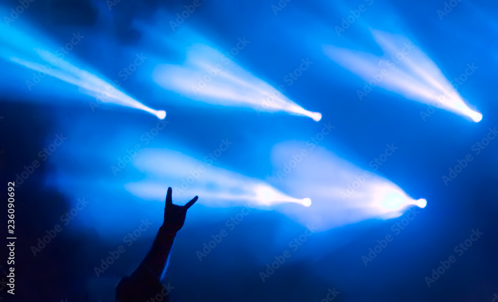 Hand showing heavy metal rock sign, a sign of the horns, with blue stage  lights in the background during Metalshow Open Air festival in Latvia.  Stock Photo | Adobe Stock