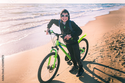 Boy rides a Bicycle along the sea on a sandy beach. photo