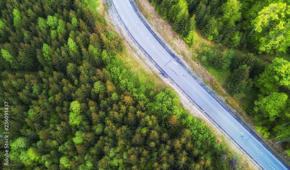Aerial view on the road in summer forest. Beautiful natural landscape from air. Green forest and road as a background from drone. Aerial view on the road in summer forest. Beautiful natural landscape from air. Green forest and road as a background from drone.