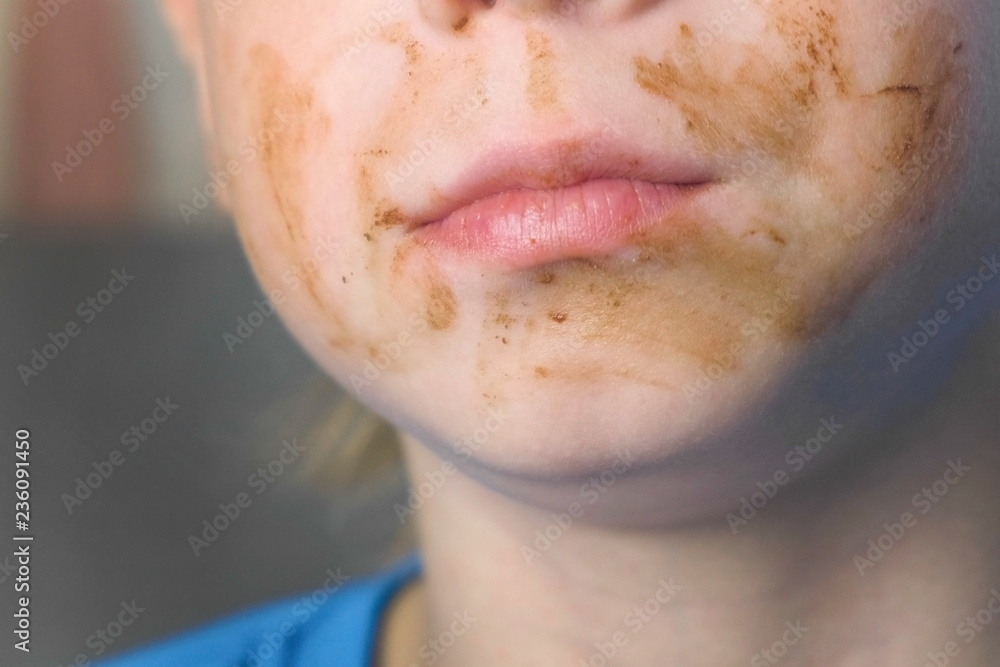Grimy happy boy with face in chocolate. Concept of unhealthy eating. Mouth Close-up. Grimy happy boy with face in chocolate. Concept of unhealthy eating. Mouth Close-up.