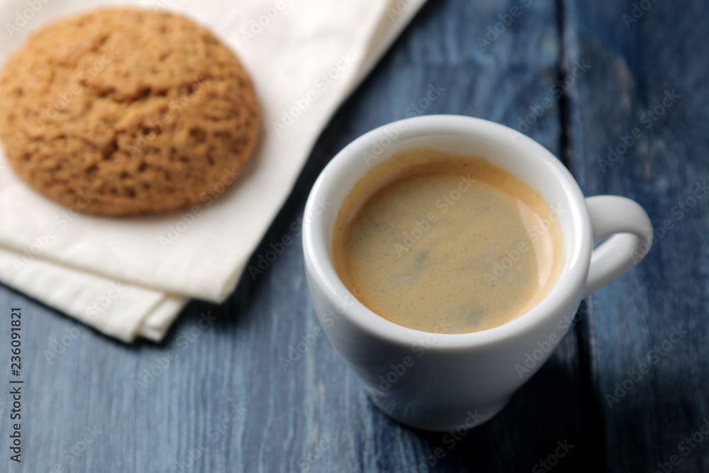 Natural espresso coffee in a ceramic coffee cup and cookies on a blue wooden table. Natural espresso coffee in a ceramic coffee cup and cookies on a blue wooden table.