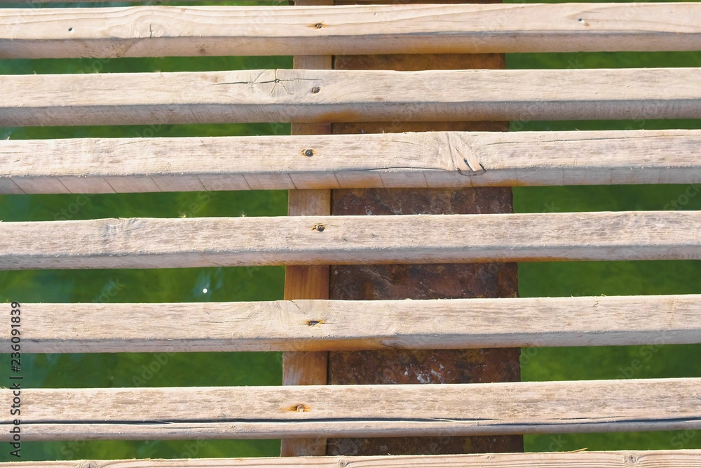 Wooden pier in the sea close-up with clear blue water under it.