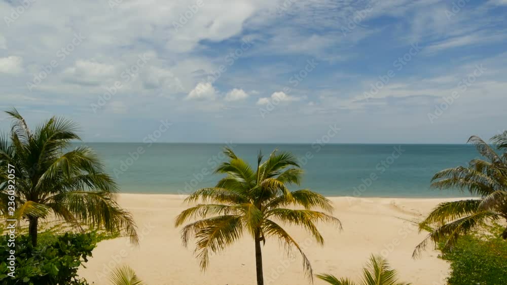 Tropical Paradise exotic white sand beach washed by blue calm sea. Sandy shore with green coconut palms under cloudy sky. idyllic landscape. holiday concept. Khanom, near Koh Samui Tropical Paradise exotic white sand beach washed by blue calm sea. Sandy shore with green coconut palms under cloudy sky. idyllic landscape. holiday concept. Khanom, near Koh Samui
