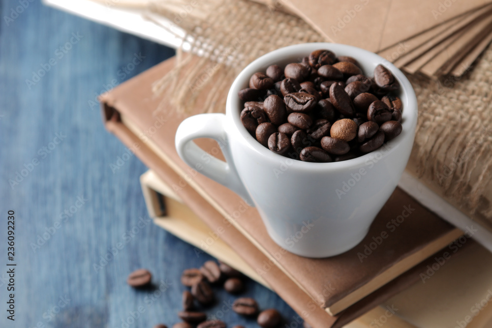 Arrangement with coffee beans in a cup and books on a blue wooden table. Arrangement with coffee beans in a cup and books on a blue wooden table.