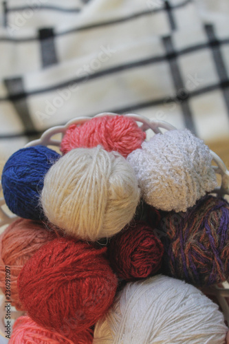 Knitting, comfort, needlework. Colored balls of yarn in a basket, knitting needles. Copyspace