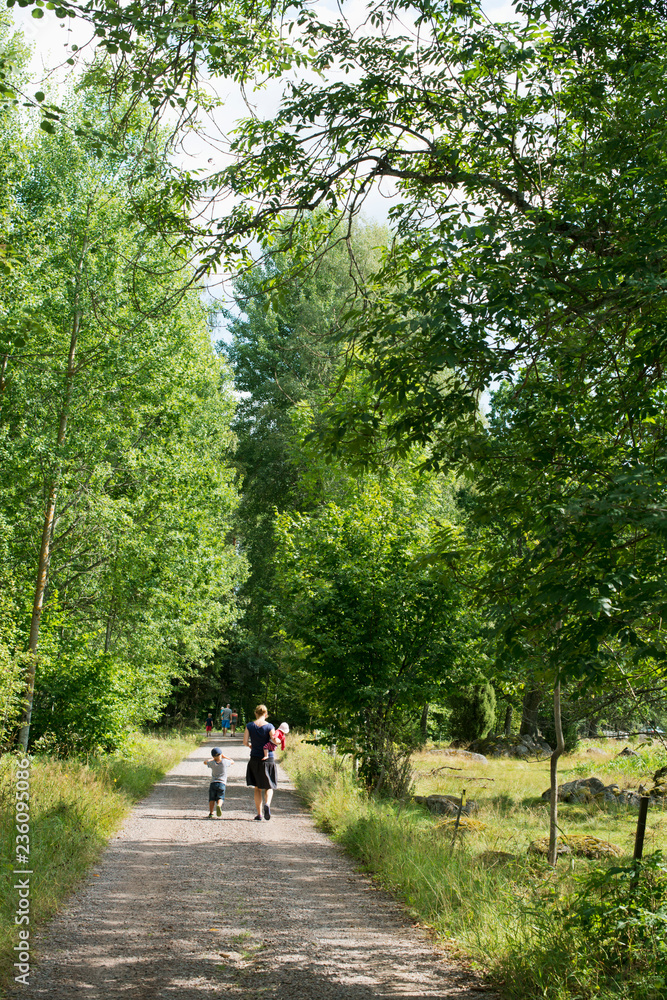 Family walking along rural road in Smaland, Sweden Family walking along rural road in Smaland, Sweden