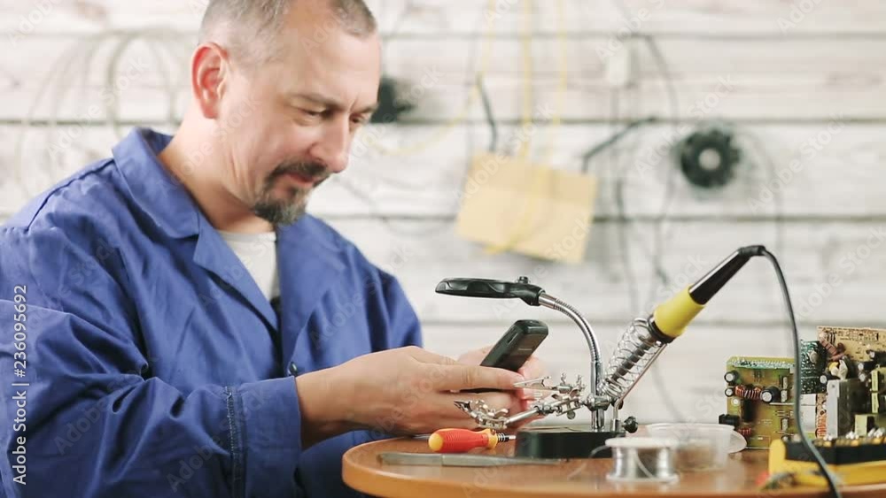 the engineer is engaged in repair of the old mobile phone the engineer is engaged in repair of the old mobile phone